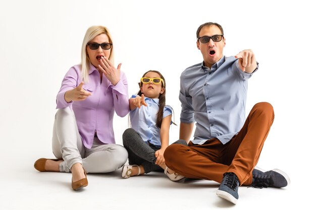 Famiglia attraente spaventata che indossa abiti casual isolati su sfondo bianco, guardando un film con occhiali 3d