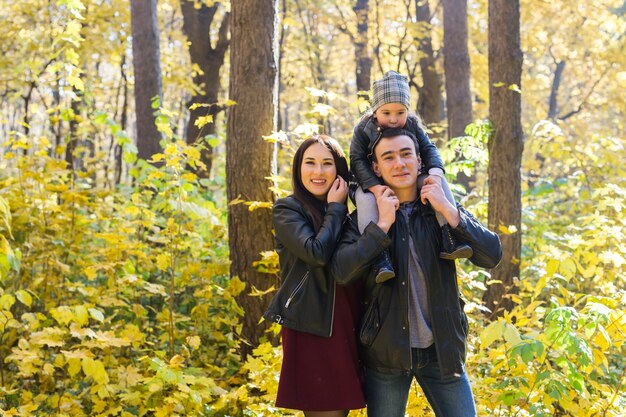 Famiglia, autunno, concetto di persone - giovane famiglia di razza mista che cammina nel parco in autunno day