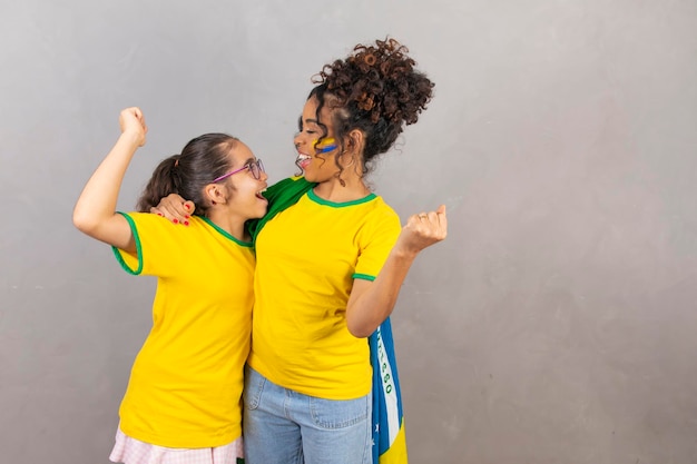 Famiglia brasiliana fan del Brasile Madre e figlia afro con abiti brasiliani Madre e figlia con i pugni chiusi che celebrano la vittoria del Brasile