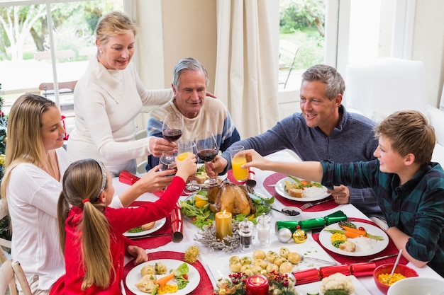 Famiglia brindando con vino rosso in una cena di Natale