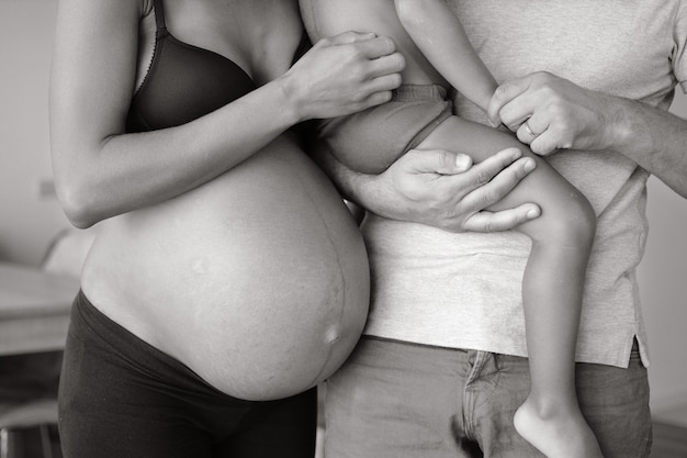 FAMIGLIA CHE ASPETTA IL BAMBINO. DONNA INCINTA CON MARITO E PICCOLO FIGLIO INSIEME A CASA.