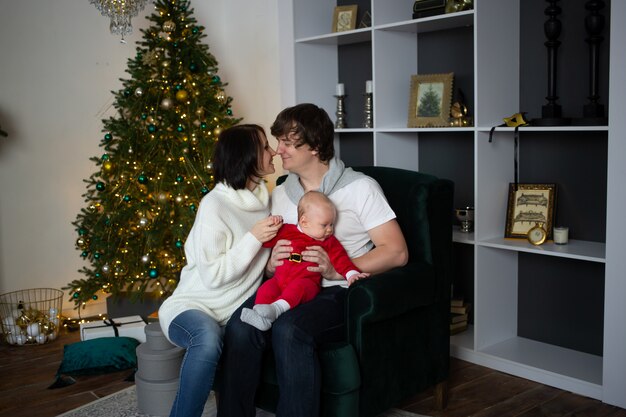 Famiglia che bacia vicino all'albero di Natale meravigliosamente decorato, natale