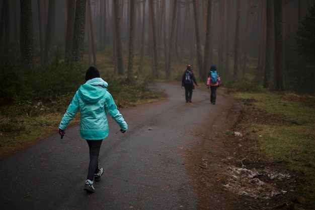 Famiglia che cammina attraverso i boschi. Pista forestale in inverno nebbioso