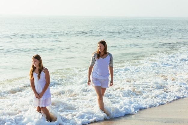 Famiglia che cammina sulla spiaggia di sera durante il tramonto. Due bambini con la mamma.