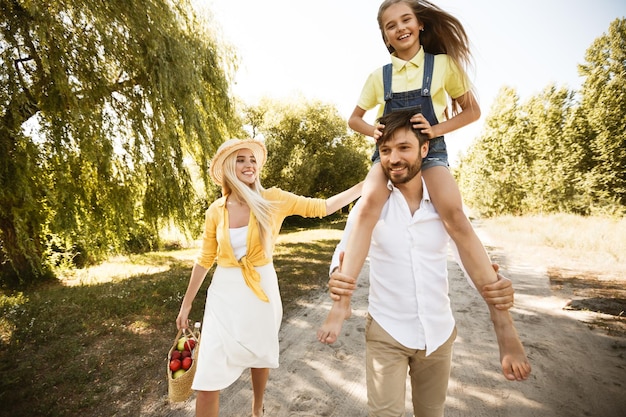 Famiglia che cammina trascorrendo del tempo insieme andando a fare un picnic in campagna