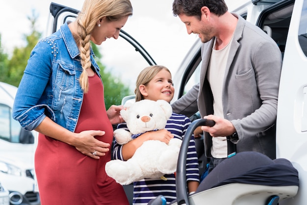 Famiglia che compra auto, madre, padre e figlio al concessionario