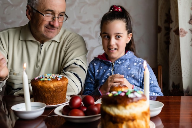 Famiglia che decora le uova di Pasqua sulla tavola, sul nonno e sulla nipote