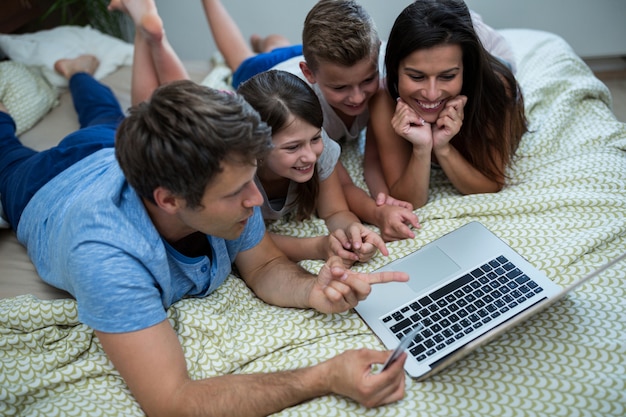 Famiglia che fa spesa online sul computer portatile in camera da letto