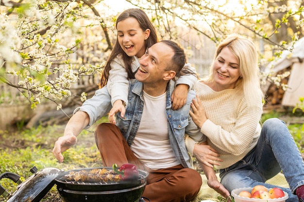 Famiglia che fa un barbecue nel proprio giardino.