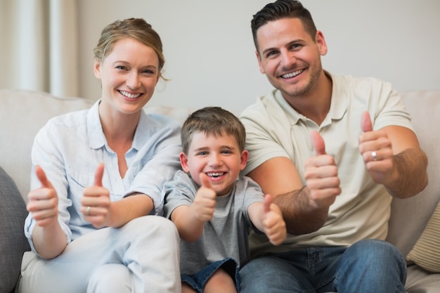 Famiglia che gesturing i pollici in su sul sofà