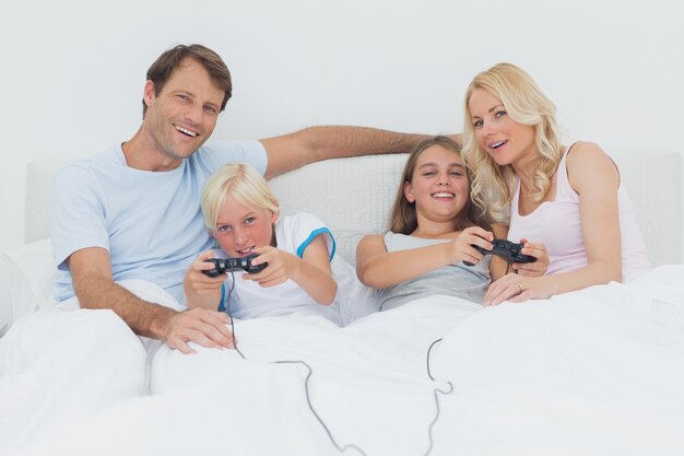 Famiglia che gioca a videogiochi a letto