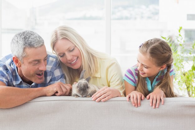 Famiglia che gioca con coniglio sul divano a casa