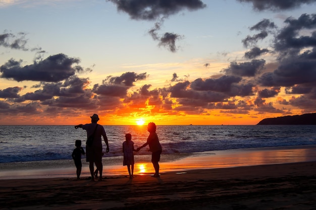 Famiglia che gioca sulla spiaggia al bel tramonto con il tramonto