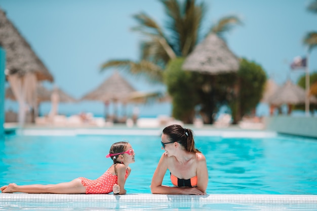 Famiglia che gode delle vacanze estive nella piscina di lusso