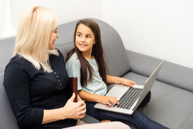 famiglia che guarda insieme un laptop argento, madre e figlia online