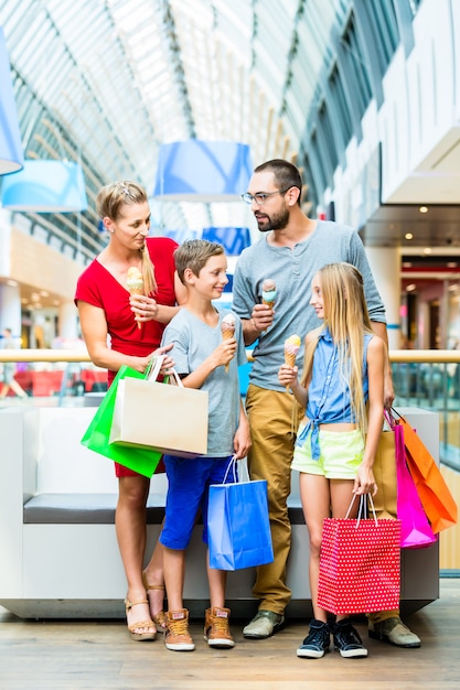 Famiglia che mangia il gelato nel centro commerciale con le borse