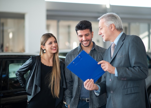 Famiglia che parla con il venditore e sceglie la loro nuova auto in uno showroom