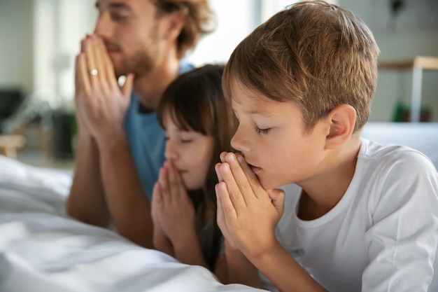 Famiglia che prega vicino al letto a casa