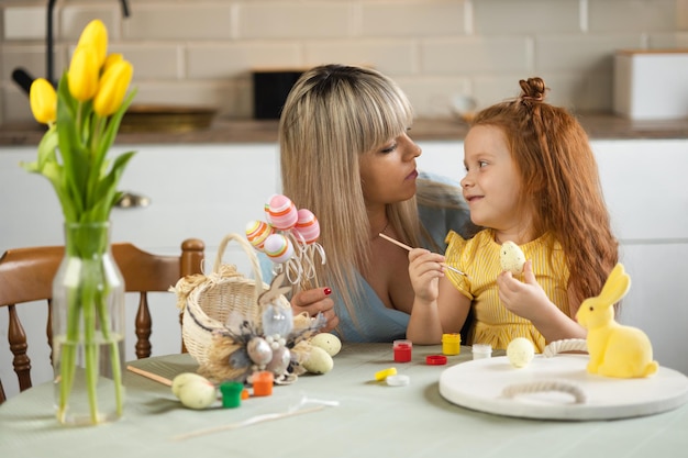 Famiglia che si prepara per Pasqua La piccola figlia e la madre dipingono le uova