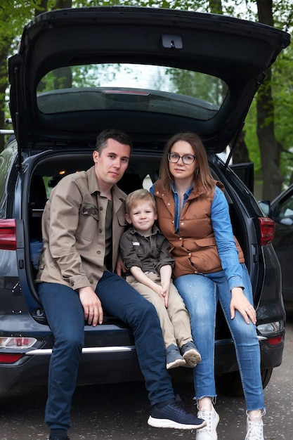 Famiglia che si siede sul bordo del bagagliaio aperto della propria auto