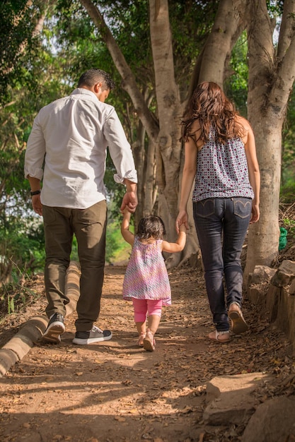 Famiglia che si tiene per mano mentre cammina in un parco durante il giorno a Lima in Perù