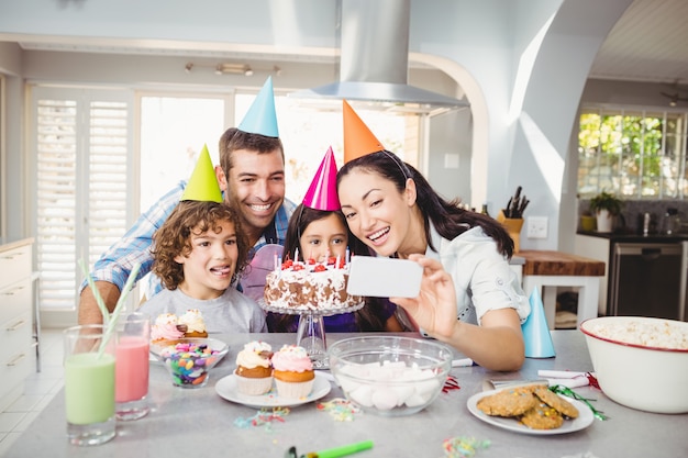 Famiglia che sorride mentre prendendo selfie durante la celebrazione di compleanno