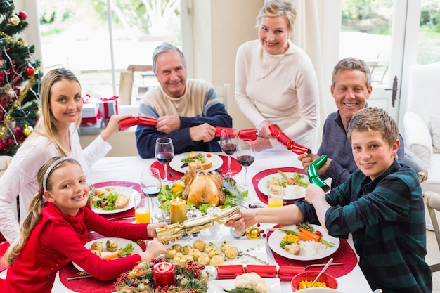 Famiglia che tira i cracker di Natale a tavola