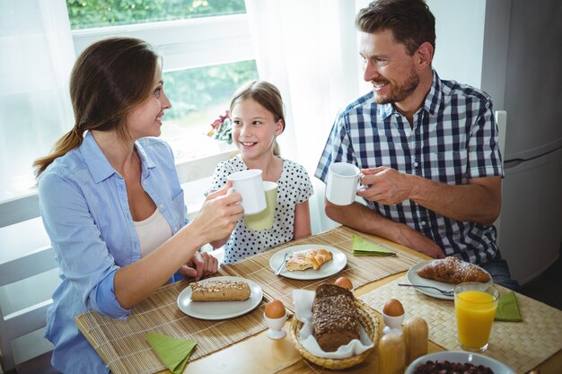 Famiglia che tosta una tazza di caffè mentre facendo colazione