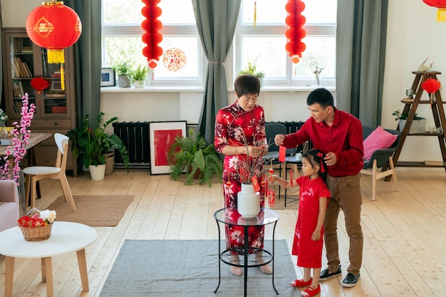 Famiglia cinese che decora il soggiorno con cartoline fatte a mano con auguri di Capodanno