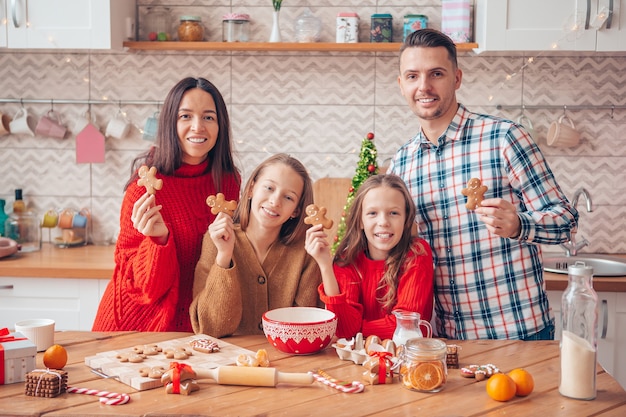 Famiglia con bambini che preparano i biscotti per Natale in cucina. Buon Natale e Buone Feste.