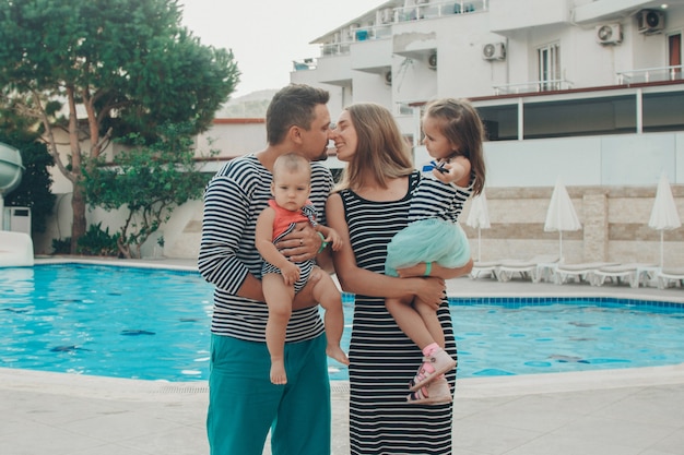 Famiglia con bambini in posa in piscina. Vacanze in hotel