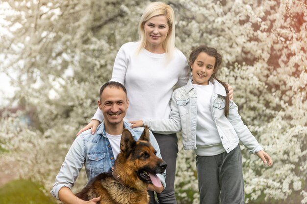 Famiglia con bambino piccolo e cane all'aperto nel frutteto in primavera.