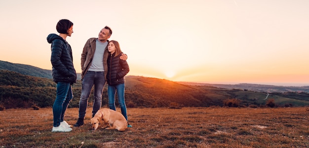 Famiglia con cane che abbraccia mentre in piedi sulla collina