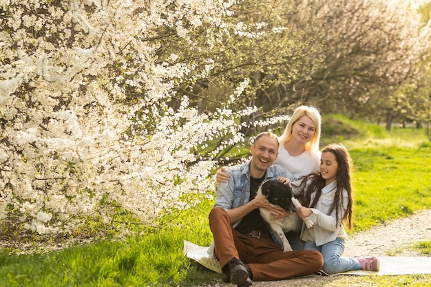 Famiglia con figlia e cane giocano insieme in giardino in primavera