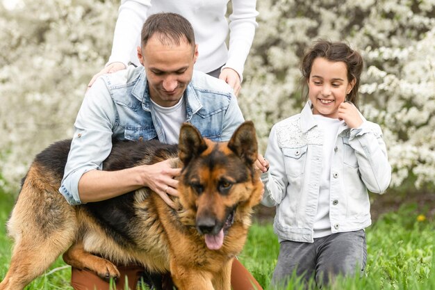 Famiglia con figlia piccola e cane che cammina all'aperto nel frutteto in primavera