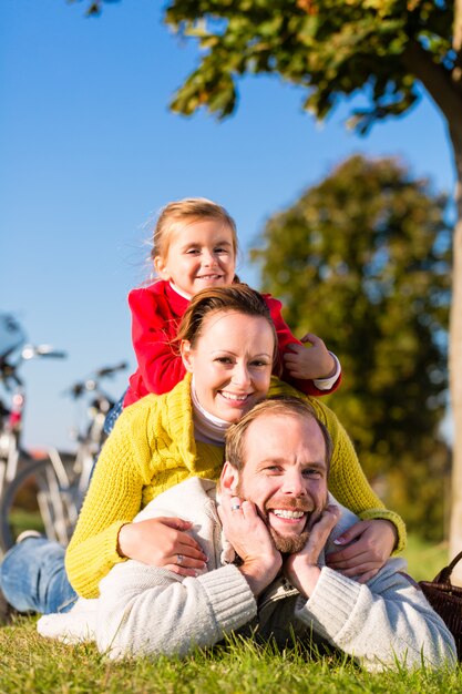 Famiglia con la bicicletta nel parco in autunno