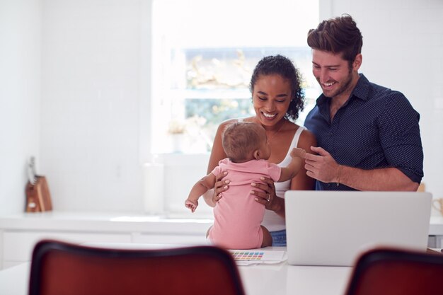 Famiglia Con La Figlia Del Bambino In Cucina Utilizzando Il Computer Portatile Sul Bancone