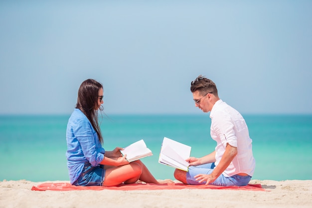 Famiglia con libri in riva al mare sdraiato