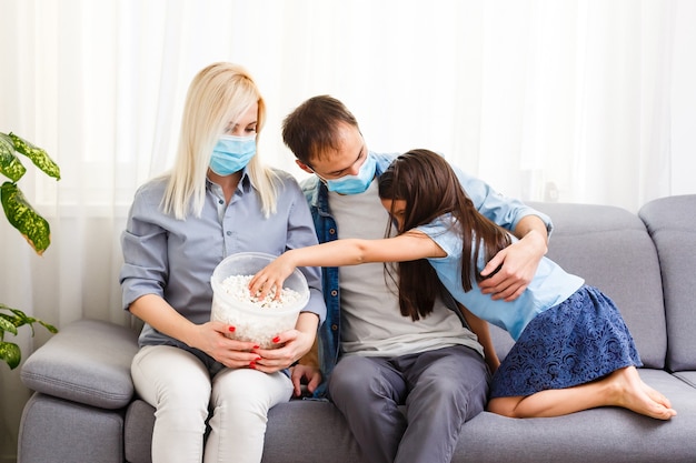 famiglia con popcorn sul divano Guardare la tv a casa. Resta a casa durante la quarantena