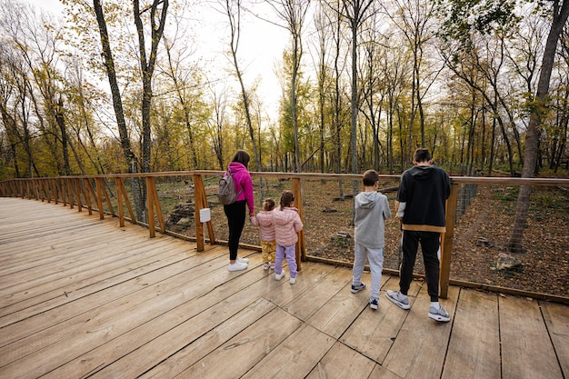 Famiglia con quattro bambini che guardano animali selvatici dal ponte di legno