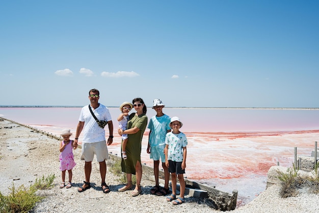 Famiglia con quattro bambini contro il lago salato rosso nelle saline Margherita di Savoia d'Italia