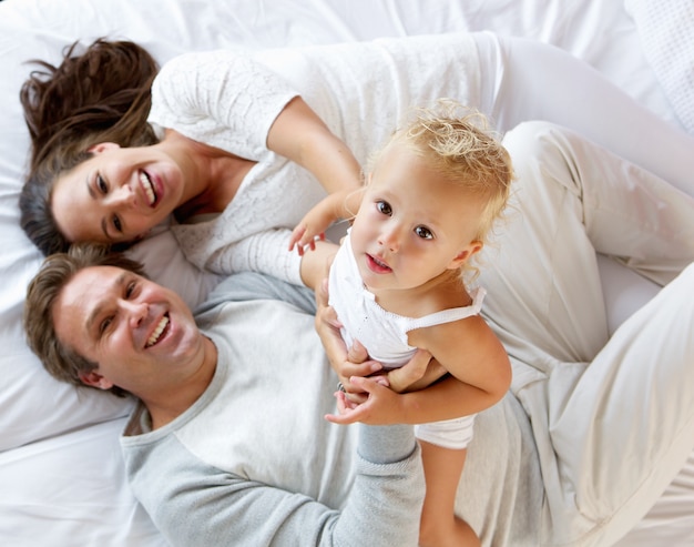 Famiglia con ragazza carina giocando a letto