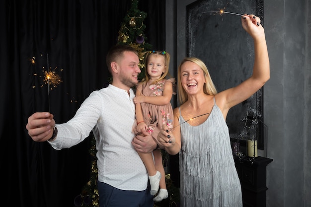 Famiglia con stelle filanti all'albero di Natale