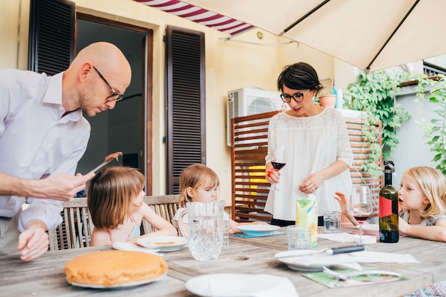 Famiglia con tavolo da salotto all'aperto per bambini femminili facendo colazione