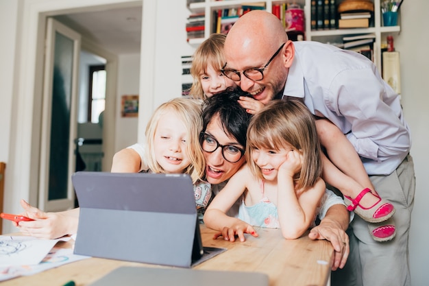 Famiglia con tre bambini al coperto facendo uso della compressa - unità, tecnologia, concetto di spettacolo