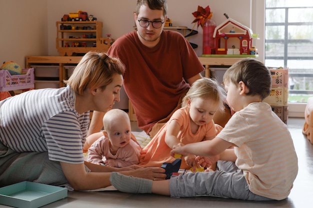 Famiglia con tre figli che giocano a casa sul pavimento