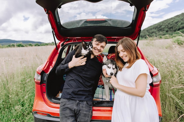 Famiglia con un gatto e un cane in natura sullo sfondo della sua auto