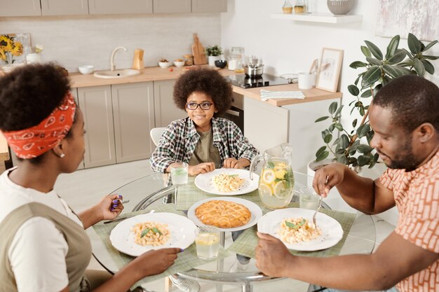 Famiglia contemporanea di tre persone che mangia pasta per cena e torta di mele per dessert