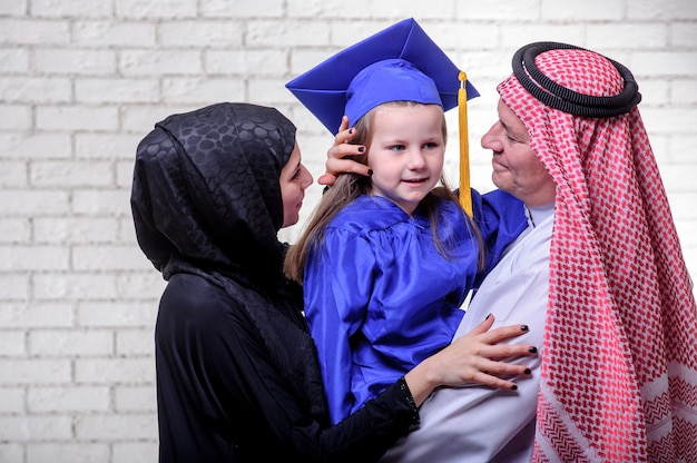 Famiglia del Medio-Oriente araba che posa con la figlia laureata su fondo bianco