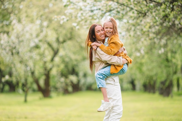 Famiglia della madre e della figlia nel giardino di fioritura della ciliegia